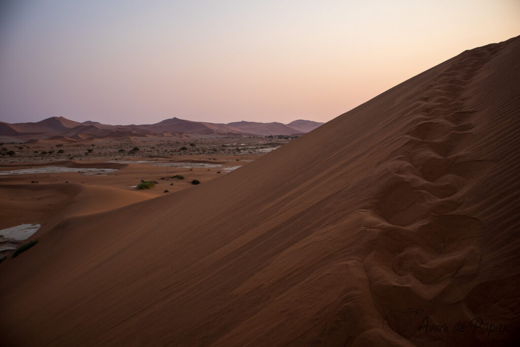 Traces de pas dans la dune au lever du soleil