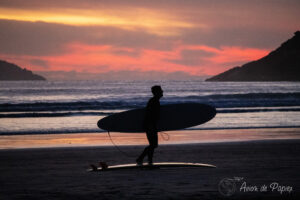 Une personne prend sa planche de surf au coucher de soleil